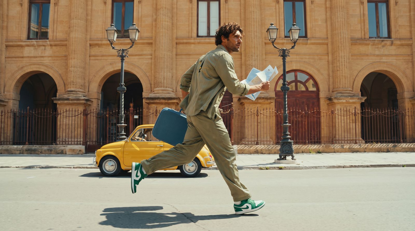 Man running with a suitcase on a city street with a yellow car and classical building in the background